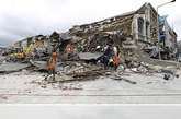 新西兰，合成图像中，（上图）2011年2月22日地震后救援人员在曼彻斯特街废墟中搜寻幸存者；（下图）相同地点地震一周年纪念日时的照片。克赖斯特彻奇是新西兰南岛最大的城市，2011年2月22日发生6.3级地震，185人死亡，周围郊区受损严重。图片来源：CFP视觉中国 