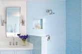 淋浴区全部采用相同尺寸的蓝色墙砖拼贴，工整中打破了白色卫浴间的单调。墙面上抠出一块四方形的小小的储物空间，将必需的沐浴用品搁置于此。
