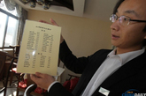 2014年1月15日，北京紫竹院公园问月楼餐厅整改定位为“茶餐厅”，该餐厅经理李学峰在展示最新的菜单。（实习编辑李丹）