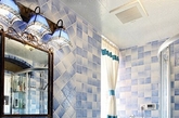 蓝白色相间的瓷砖铺满了整个卫浴空间的墙面与地面，让这一卫生间整体呈现出一种清爽蓝色系，是很适合卫生间的色调。镜面上方的三盏组合式的灯具也以蓝色系为主，使整个空间感都显得优雅统一。（实习编辑：温存）