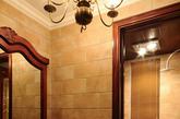 拥有裂纹纹理的卫浴柜台面，与木质大镜面结合，带有一种古朴且赋有设计感的调调，顶部的暖色吊灯与这一空间加在一起显得很相配，简约又不失别致感。