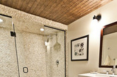 木质地板与木质天花板都让这间卫生间透出一种自然舒适的气息，以白色粗糙墙面打造出的玻璃淋浴房在这间卫生间中也显得大气，在白色墙面上嵌上一幅优雅的黑白画幅让整个卫生间都拥有了一种雅致感。