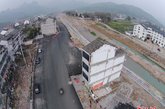 3月10日，在浙江41省道南复线溪南村处，2栋房屋耸立在一条新建好的路中央，给车辆通行带来安全隐患。41省道南复线是省重点建设项目，总投资8.89亿元，全长15.165公里。