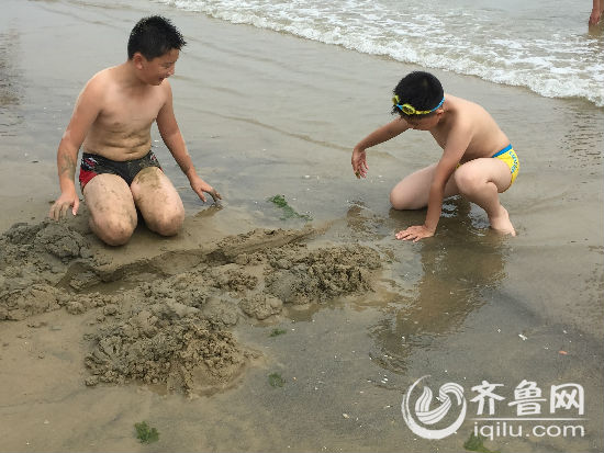 孩子在沙滩上挖起“鱼塘”
