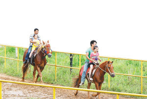 天涯驿站元门跑马场，游客在驯马师的陪伴下骑马。 本报记者 苏晓杰 摄