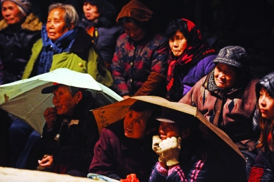 夜场演出时下起小雨,村民们撑着伞听戏到最后.