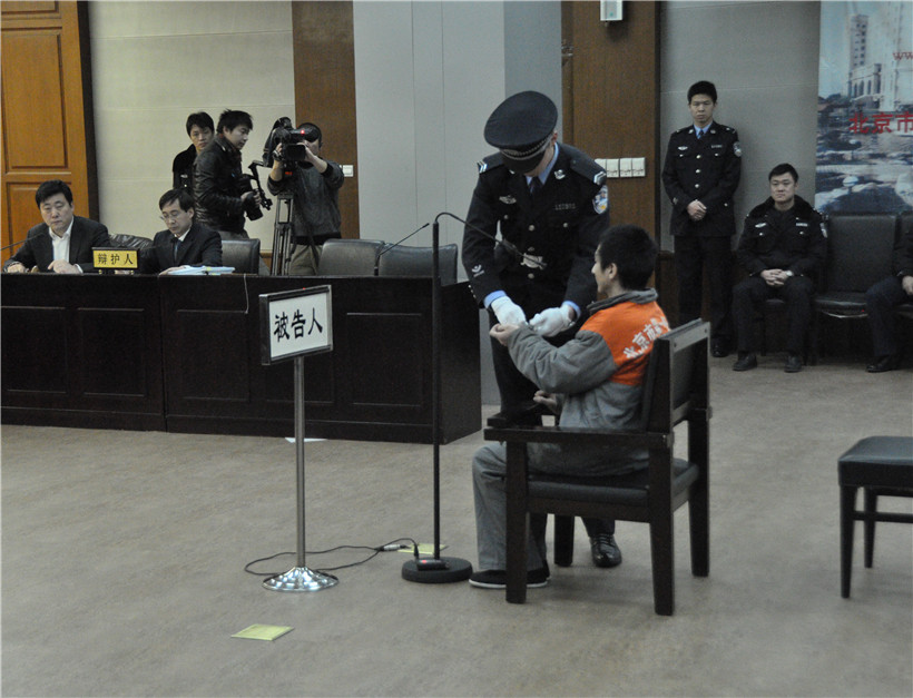 法警为犯罪嫌疑人解开手铐。人民网记者杨成摄