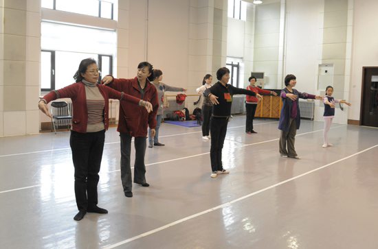 女摄影家们体验芭蕾，芭蕾大师在排练厅指导女摄影家。