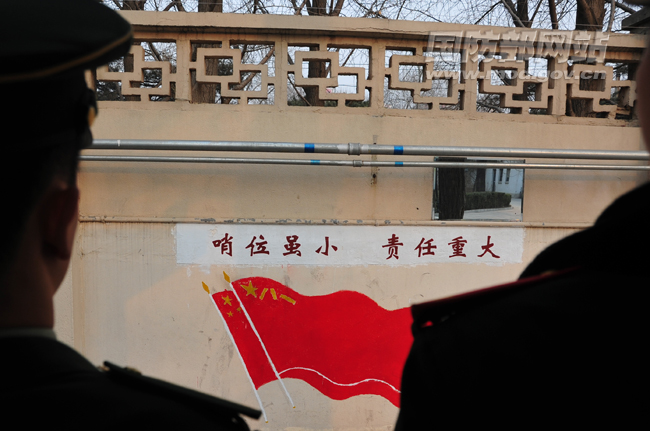 围墙哨对面的墙壁写着“哨位虽小,责任重大”,墙外就是繁华的城市。