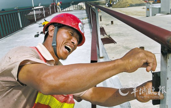 在西人工岛工地,烈日当空,晒得黝黑的丘师傅正在仔细度量钢架