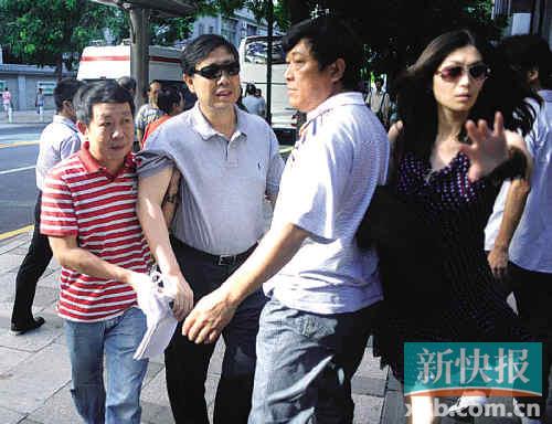 ■2011年8月23日，潘潇（左二）在几人的护卫下走进广州中院受审。黄巍俊 罗伟雄/摄