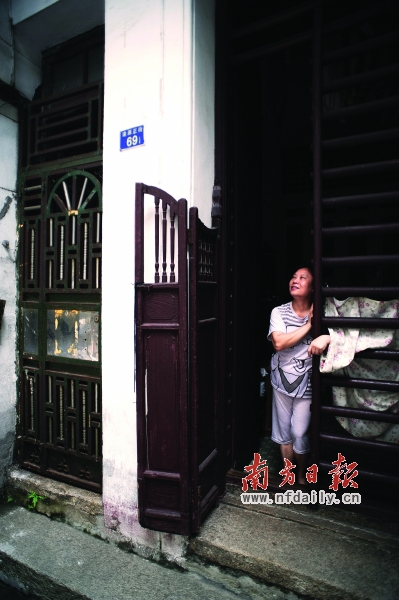 曾阿姨靠在趟栊门前,向记者讲述着西关大屋的历史.