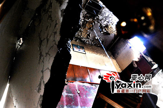 图为从一楼的住户家可以看到自二楼坍塌下来的楼板和床铺等物，男女主人的一张婚纱照虽然还挂在二楼的墙上，但其楼顶也向上突出10余厘米。亚心网记者 张万德 摄