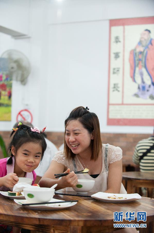 7月31日,顾客在传统文化宣传画前享受午餐。一家名叫妈妈的菜园的素食全自助餐馆6月中旬在广东肇庆开业,所谓的全自助是指交餐费、取餐具、取食物和吃完后收拾桌面、回收餐具等过程不依靠服务人员参与,而是全凭顾客自觉。这家餐馆的老板是一位来自广东普宁的年轻人郭福龙。2012年从肇庆学院毕业后,他在一家快餐店工作了近一年时间,期间就琢磨着把自己热爱的传统文化和餐饮结合起来。2013年,在自己的努力和亲朋的帮助下,这家宣传传统思想和素食文化的餐馆开张,就餐价格为大人15元,老人和儿童减半,老师和学生10元