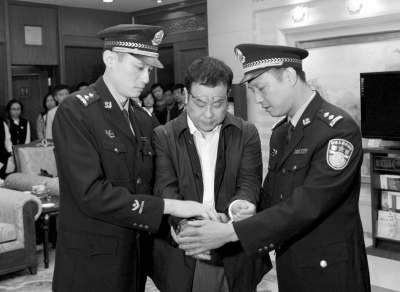 在上饶市检察院逮捕决定书上签字后,李华波被戴上手铐.新华社发