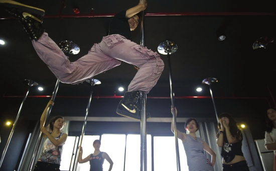 教练在给钢管舞学员做示范动作.图/记者 陈杰