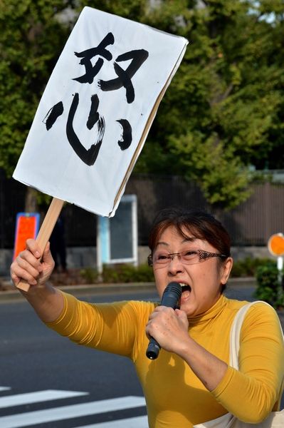 10月20日,一名日本市民在日本东京的首相官邸前手举标语喊出抗议口号