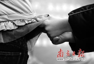 一名自闭症儿童紧紧抓住家长的衣服不愿松手